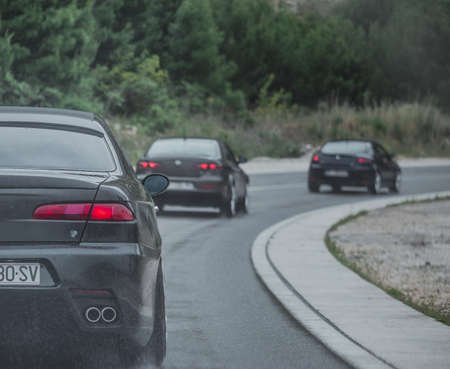Multiple Alfa Romeos driving in a column. Enthusiasts owners meeting and driving to festival on a...