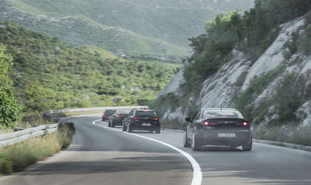 Multiple black Alfa Romeo 159s driving together in a formation on a rural road. Enthusiasts in...