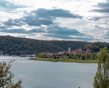 Town of Skradin seen from a nearby uphill road. River Krka flowing around the small town, belltower...