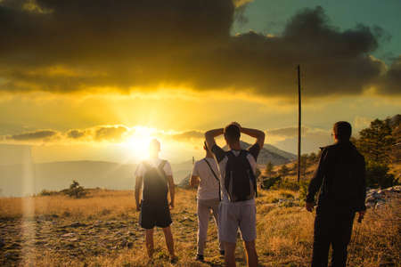 Four friends seen from behind, hiking on top of the Mosor mountain in Croatia. Strong colorful sun...