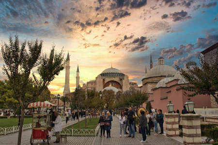 Istanbul, Turkey October 2019 Iconic Hagia Sophia museum and church seen massive in the distance. Garden area in front of it full with tourists and sellers. Beautiful golden sunset late afternoonのeditorial素材