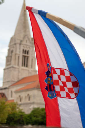 Closeup of the Croatian flag waving in the wind with the church in the village of Selca, Croatia in the background. Celebrating Croatian victory in the war of independenceの写真素材