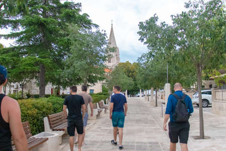 Selca, Croatia August 2020 A group of friends seen from behind walking through a small village on...
