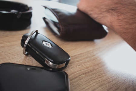 Supetar, Croatia August 2020 Car keys from a Renault Clio, wallet and phone laying on a wooden table. People emptying their pockets upon sitting down in a coffee shopのeditorial素材