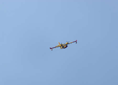 Close up of a fire fighting water bomber airplane flying over head, dropping water on wildfires in...