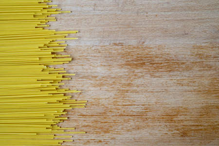 Close-up of Uncooked Spaghetti On A Scratched Wooden Cutting Board, Top Viewの写真素材