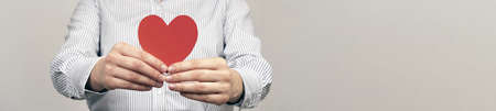 Young woman holding red heart in hands. Symbols: Love and relationships, medicine and heart disease...