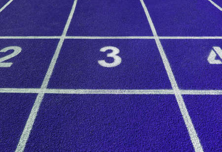 White number 3 on the blue rubber surface of a treadmill in a street stadium arenaの写真素材