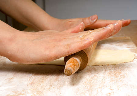 Female hands prepare dough for home baking, rolling pin for dough in hands