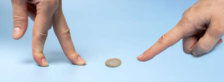 female fingers and 1 euro coin on a blue background: financial consulting concept, profit, loss of...