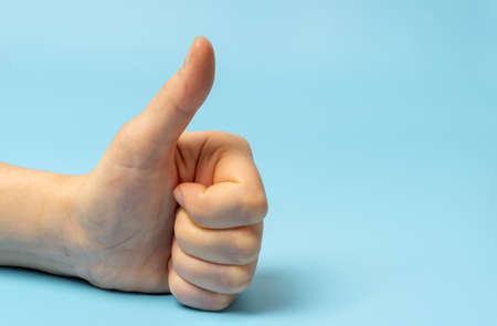 Female hand shows like gesture, on blue background.の写真素材