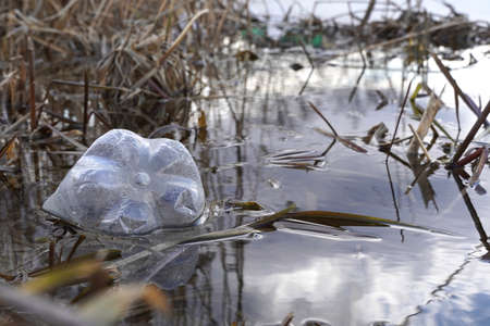 plastic bottle floating in river at the water surface, environmental problem with plastics pollution lakes and rivers.の写真素材
