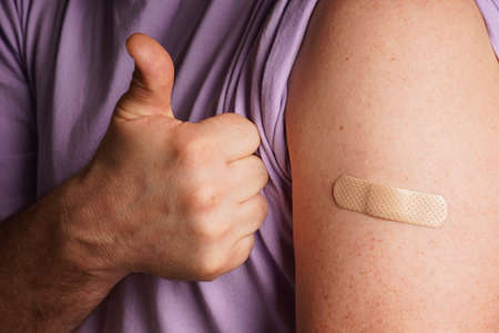 bandage on a man's arm after scratch on skin or injection for vaccine. A medical patch or plaster on...