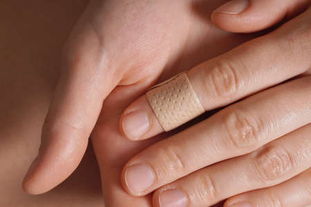 Female hands with a medical plaster on finger.の写真素材