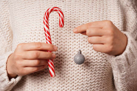 Female hands hold Christmas tree toy and candy.の写真素材
