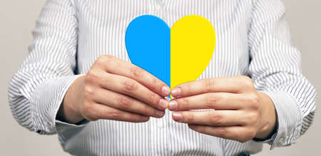 Woman holding heart in blue and yellow colors in hands.の写真素材