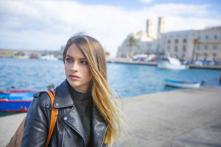 Beautiful girl on vacation in Molfetta near the port with the Duomo behindの写真素材