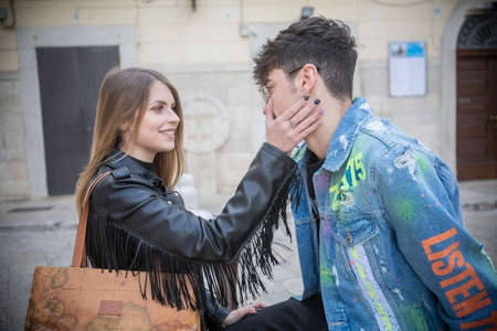 a close-knit Italian couple made up of a woman and a man standing in a narrow street of a historic center to walk and exchange affectionate cuddlesの写真素材