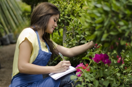 Young female gardener taking notes and doing inventory at workの写真素材