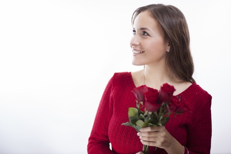 Pretty young woman in red holding a bouquet of roses and looking towards copy spaceの写真素材