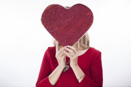 Young woman covering her face with a big red heartの写真素材