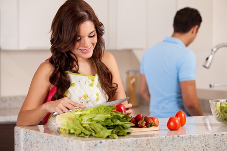 Young Latin woman cutting some vegetables to make a salad for dinnerの写真素材