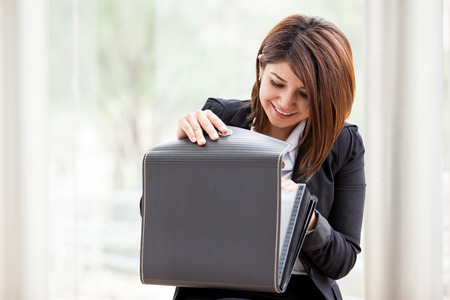 Pretty Latin businesswoman looking for some important documents on a briefcaseの写真素材