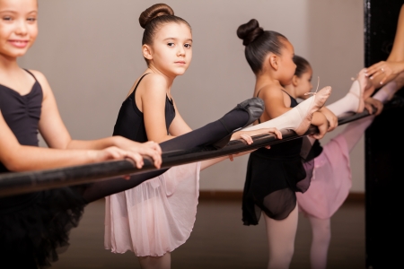 Cute little ballet dancers practicing some dance moves in a barre in a dance classの写真素材