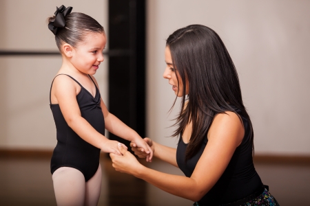 Beautiful female dance instructor talking to and coaching one of her students in a dance academyの写真素材