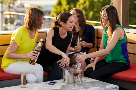 Group of four female friends having fun and drinking alcohol in a terrace in the afternoonの写真素材