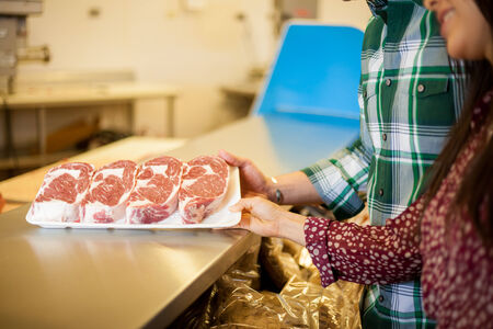 Closeup of a couple of young adults looking at some meat cuts at the supermarket