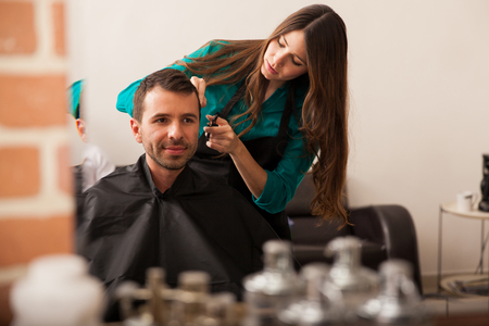 Young Hispanic man looking at himself in a mirror in a barber shopの写真素材