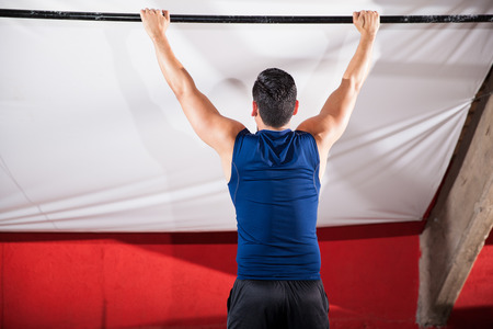 Athletic young man about to pull himself up a bar at a cross-training gym