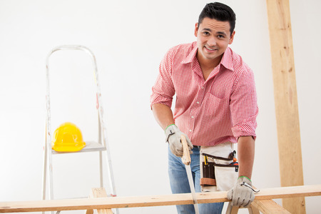 Handsome Latin carpenter cutting some wood boards at workの写真素材