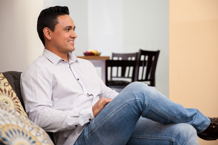 Young attractive man relaxing at home and sitting in a couchの写真素材