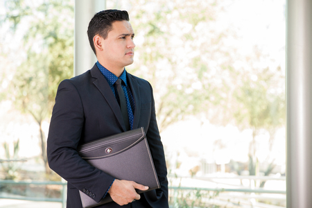 Handsome young lawyer carrying documents in a portfolio and looking towards copy spaceの写真素材