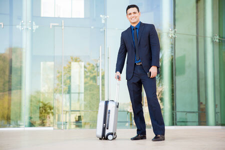 Full length of a young businessman with a suitcase waiting for his flight and smilingの写真素材