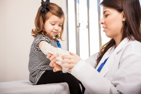 Profile view of a female pediatrician putting a bandage on a little girlの写真素材