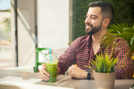 Portrait of a young handsome man enjoying a healthy smoothie at a restaurantの写真素材