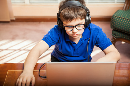 Little boy with glasses having some fun playing video games on a laptop