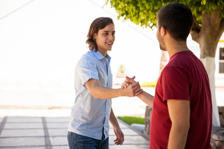 Couple of handsome male friends greeting with a handshake at school. Lots of copy spaceの写真素材