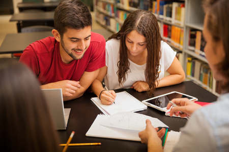 Group of young adults studying together and having a good time in the school libraryの写真素材