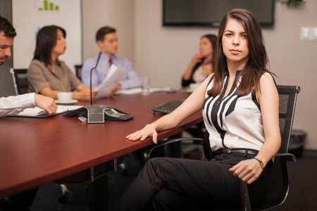 Portrait of a confident and powerful female lawyer sitting in a meeting room with some of her clientsの写真素材