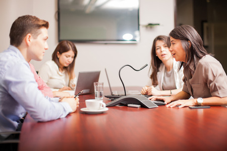 Group of people talking to a microphone over a conference call at workの写真素材