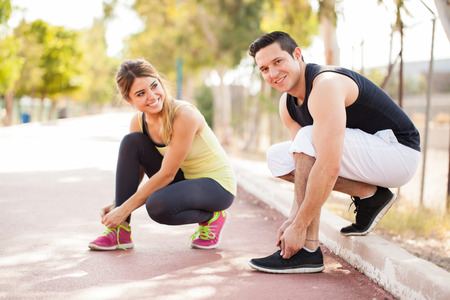 Cute young couple tying their shoes and getting ready for some running and working out togetherの写真素材