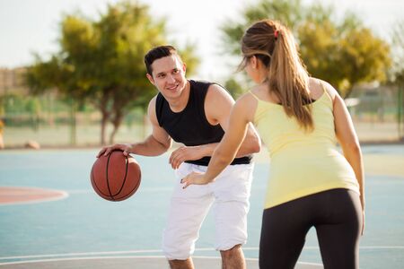 Portrait of a handsome young man trying to score some points during a basketball game against his dateの写真素材