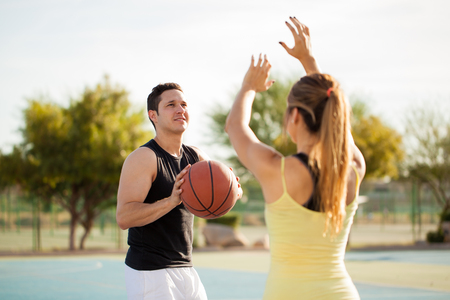 Young Latin man about to score some points on a basketball game against his girlfriendの写真素材