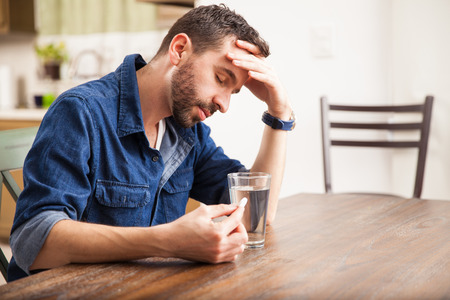 Good looking man with a beard feeling sick with indigestion and about to drink an effervescent tablet at home Good looking man with a beard feeling sick with indigestion and about to drink an effervescent tablet at home