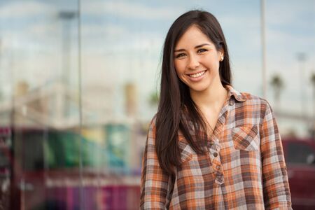 Portrait of a cute young Hispanic brunette dressed casual and standing outside a clothing store in a...