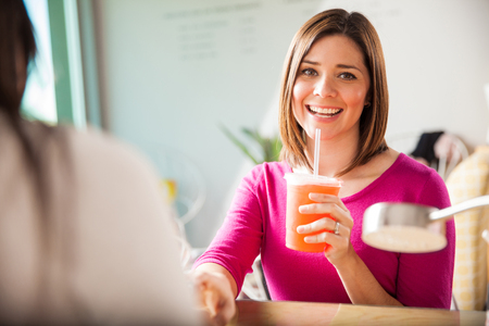Gorgeous brunette relaxing with a cold drink while getting a manicure during her visit to a nail salonの写真素材